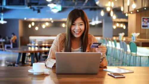 Woman sitting at table while using her credit card.