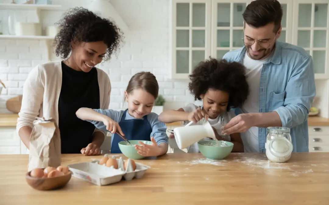 Family stands at kitchen counter and mixes ingredients together.
