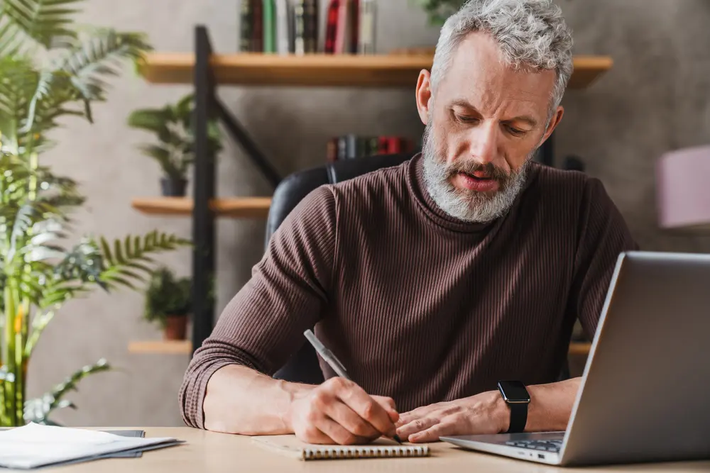 A man sitting at his desk and writing.