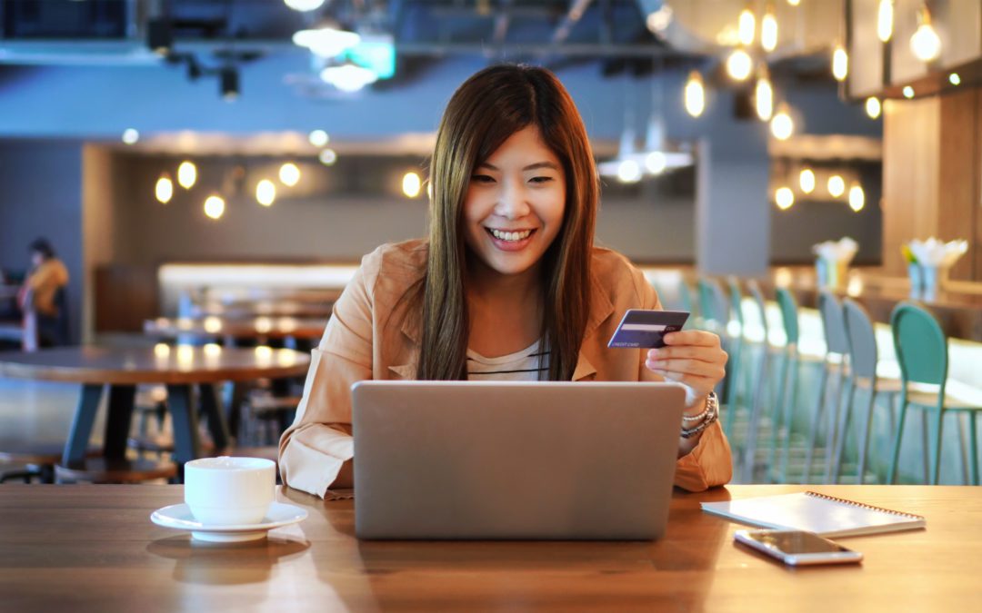 Woman sitting at table while using her credit card.