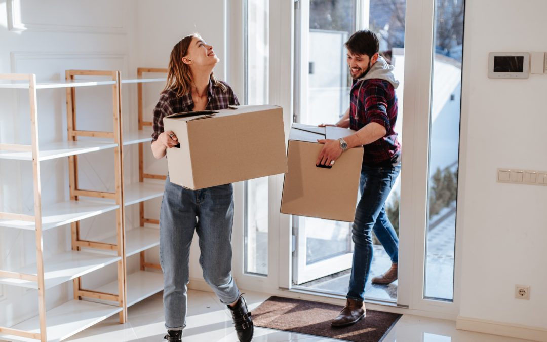 Woman and man bringing boxes in through door.