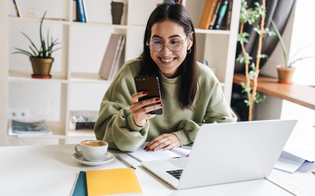 College student sitting at desk on her phone.